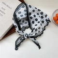 Lightweight floral neck scarf with black flower print and wave edges tied in a bow - White with Black Petal Border