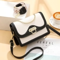 Bolso bandolera bicolor con cadena dorada y dos correas sobre una mesa minimalista - Blanco