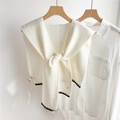 Dettaglio dello scialle in maglia crema con bordi smerlati neri su colletto bianco - Bianco Crema Impunturato