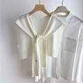 Dettaglio dello scialle in maglia crema con paillettes su una camicia bianca in gruccia - Bianco