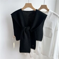 Détail d'un châle en tricot noir avec surpiqûres blanches et nœud décoratif sur le devant - 43x102cm / Noir