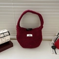 Detail of burgundy knitted tote bag featuring a toggle closure and egg logo label - Burgundy