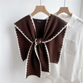 Close-up of a dark brown knitted shawl with white contrast stitching on a wooden hanger - Brown (White Stitch)