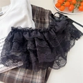Dettaglio di gonna a balze in pizzo nero con fiocco, sovrapposta a pantaloni casual - Pizzo a Più Strati Nero