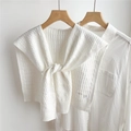 Primo piano dello scialle in maglia beige con trama a nido d'ape su camicia bianca - Bianco Sporco