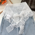 Détail d'un châle en dentelle blanche avec broderie florale et bordure à volants sur jean - Style Fleurs Jumelles