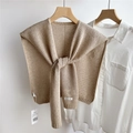 Detail of beige knit shawl showing intricate hollow weave texture and brand label on a hanger - Coffee