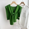 Dettaglio dello scialle in maglia di lana verde con nodo decorativo su camicia bianca - Verde