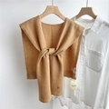 Detail of camel wool knit shawl over white shirt showing the texture and logo tag - 43x110cm / Camel