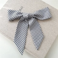 Chic white bow hair ribbon with black polka dots and long streamers on linen background - White Polka Dot
