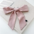 Détail du ruban à cheveux rose à pois en satin avec étiquette sur un livre texturé - Rose à Pois