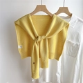 Detalle de chal de punto amarillo con botón metálico y etiqueta sobre camisa blanca - Amarillo