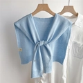 Detalle de chal de punto azul claro con lazo sobre camisa blanca en percha de madera - Azul Claro