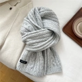 Dettaglio di sciarpa in maglia a trecce grigio chiaro con etichetta tessuta su fondo bianco - Grigio
