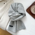 Dettaglio di sciarpa in maglia grigio chiaro con motivo a trecce ed etichetta - Grigio chiaro