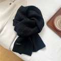 Detail of black knit wool blend scarf with woven logo tag on a cozy soft background - Black