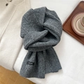 Detailed knit texture of dark grey wool scarf with brand label on soft white linen - Dark Gray