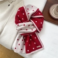 Dettaglio di sciarpa in lana a pois rosso e crema con texture in maglia morbida su letto - 186cmx23cm / Rosso