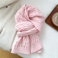Detailed texture of pink chunky knit wool scarf with brand label on a cozy background - Pink