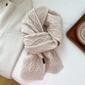Macro-opname van beige gebreide wollen sjaal met kabelpatroon en een geweven label - Beige