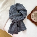 Detailed macro view of dark grey wool scarf with classic cable knit and woven label - 21x160cm / Gray