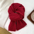 Detail of red cable-knit wool scarf texture and white 100% Wool material label - 21x160cm / Red