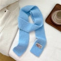 Detailed close-up of light blue ribbed knit scarf with a vintage rectangular patch - Blue