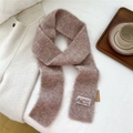 Detail of a chunky knit scarf with a Vintage label on a soft textured rib surface - Coffee