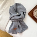 Detail of grey knitted scarf with ribbed texture and premium brown leather label - 23x156cm / Gray