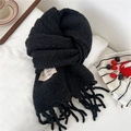 Detail of black thick knit scarf with fringe and minimalist woven label on white fabric - 28*210cm / Black