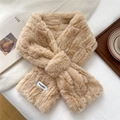 Detail of light khaki plush scarf with a criss-cross design on a cozy white blanket - Camel