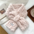 Close-up of pink faux fur scarf with ribbed texture, cross-buckle design, and brand label - Pink
