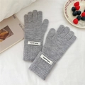 Close-up of thick grey knit winter gloves with white 'Hello' woven label detail - One Size / Gray