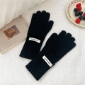 Détail de gants en tricot noirs avec poignets côtelés et étiquette décorative minimaliste - Taille unique / Noir