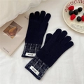 Detail of navy knit gloves with gray checkered cuffs and branded label on a cozy background - Navy Blue