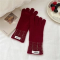 Gros plan de gants tricotés rouges avec poignets à motifs et étiquettes tissées - Taille unique / Bordeaux