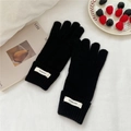 Detail shot of black knitted wool gloves with elastic ribbed cuffs on a soft fabric - One Size / Black