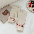 Close-up of cream knit winter gloves featuring red hand-stitched detailing on the cuffs - Creamy White (Red Stitching)