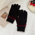 Detail of black knit gloves with contrast red hand-stitched wrist seams on white fabric - Black (Red Stitching)
