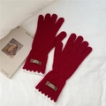 Détail de gants en tricot rouges avec bordure en dentelle blanche et étiquette en cuir - Bordeaux