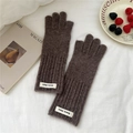 Close-up of brown knit gloves with ribbed cuffs and branded label on white cotton fabric - Dark Coffee