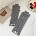 Close-up of grey knit gloves with elongated ribbed cuffs and brand label on white fabric - One Size / Finger Touchscreen Style / Gray
