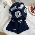 Detalle de bufanda de lana de punto azul con motivos florales y logo metálico de marca - Azul marino