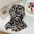 Dettaglio sciarpa leopardata in maglia di lana con etichetta su letto bianco - Leopardo Beige
