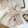 Detalle de bufanda de lana crema con etiqueta 100% lana y textura suave y fina - Beige