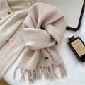 Primer plano de bufanda de punto beige con borlas suaves y detalles de textura tejida - Beige