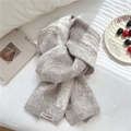 Nahaufnahme des dick gestrickten Schals mit grau-weißem Rautenmuster und Stoffetikett - Grau