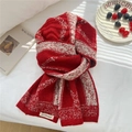 Macro detail of red and white jacquard knit scarf showing thick soft texture and brand label - Red