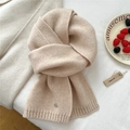 Dettaglio della sciarpa in lana beige lavorata a maglia con bordi a coste e pendente - Beige