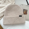 Primer plano del gorro de lana beige mostrando la etiqueta 100% lana y el tejido - Beige